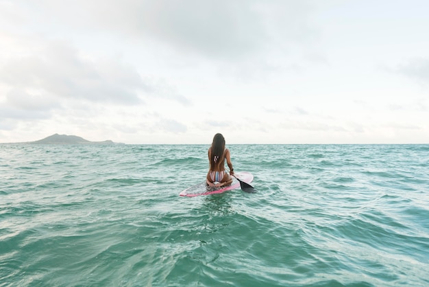 Mujer en traje de baño surfeando en hawaii