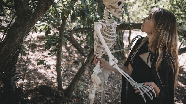 Mujer en traje de bruja con esqueleto por encima de la cabeza