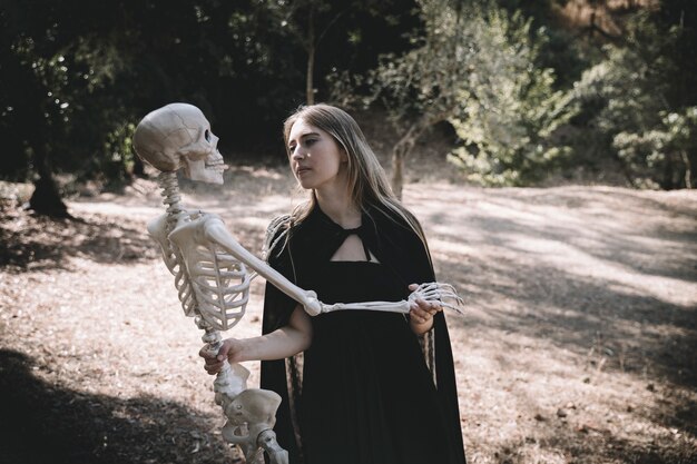 Mujer en traje de bruja con esqueleto de precisión