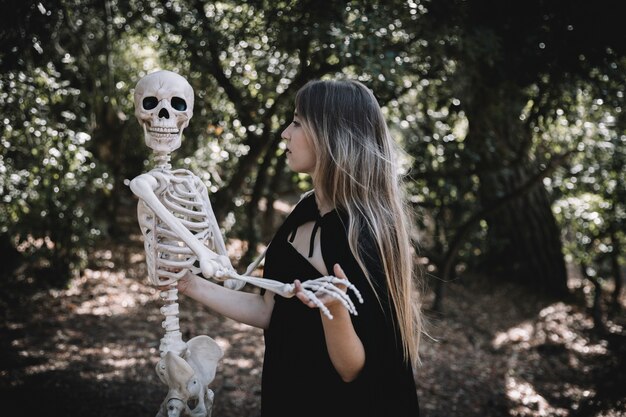 Mujer en traje de bruja con esqueleto