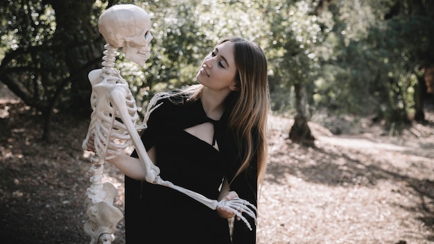 Mujer en traje de bruja mirando el esqueleto