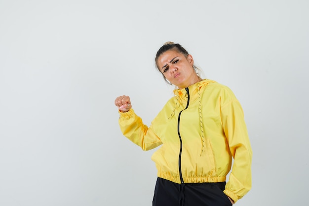 Foto gratuita mujer en traje deportivo amenazando con el puño y mirando enojado, vista frontal.