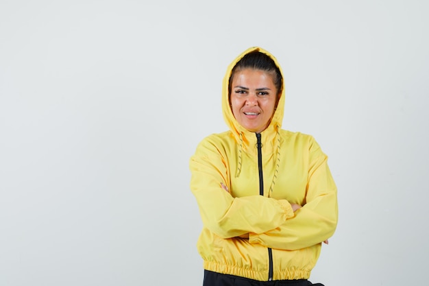 Mujer en traje deportivo de pie con los brazos cruzados y mirando alegre, vista frontal.