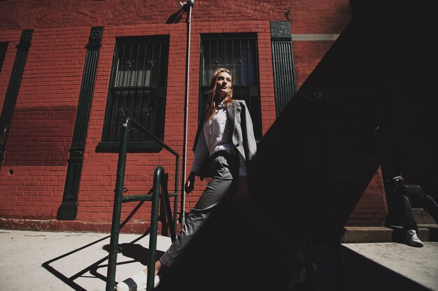 Mujer en traje gris goza de viento en la calle de la ciudad de Nueva York