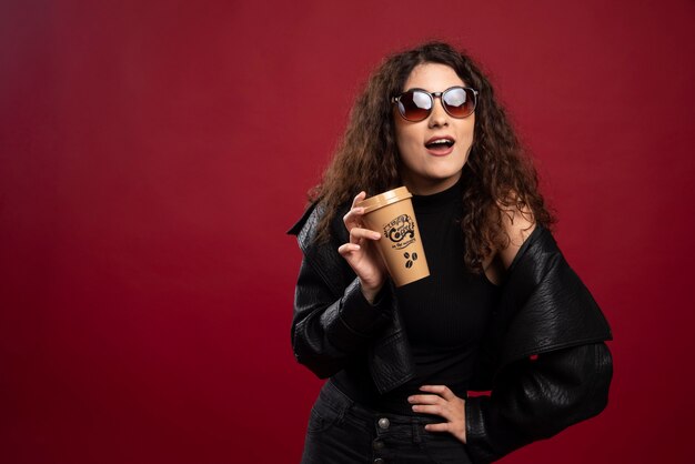 Mujer en traje negro posando con una taza y vasos.