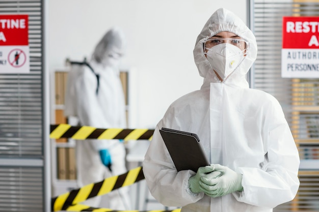 Mujer en traje de protección sosteniendo una tableta