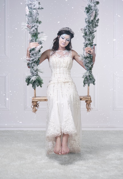 Mujer en traje de reina de las nieves en columpio