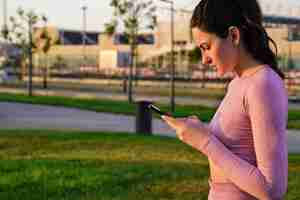 Foto gratuita una mujer en traje de yoga lo hace temprano en la mañana con un teléfono en las manos al amanecer.