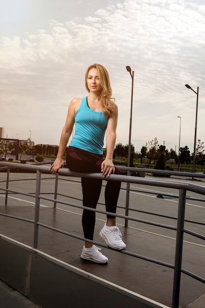 Mujer en trajes de fitness azul y negro sentado en un metálico por lo tanto.