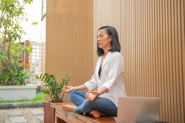 Mujer tranquila con los ojos cerrados practicando yoga en posición de loto