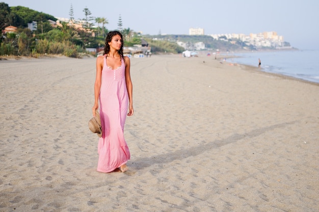 Mujer tranquila en la playa con el sombrero en la mano