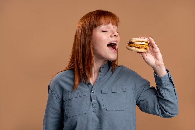 Mujer con trastorno alimentario tratando de comer hamburguesa