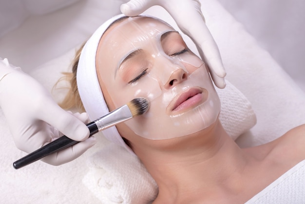 Mujer durante un tratamiento de máscara de piel de belleza en su rostro con un cepillo