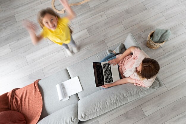 Mujer tratando de trabajar en la computadora portátil desde casa mientras sus hijos corren