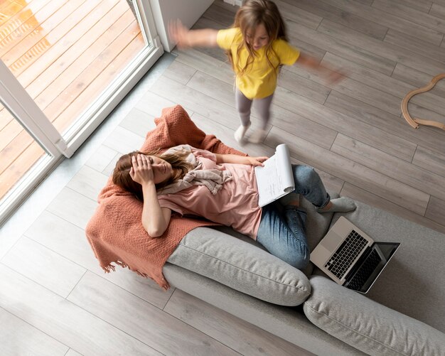 Mujer tratando de trabajar en la computadora portátil desde casa mientras sus hijos corren