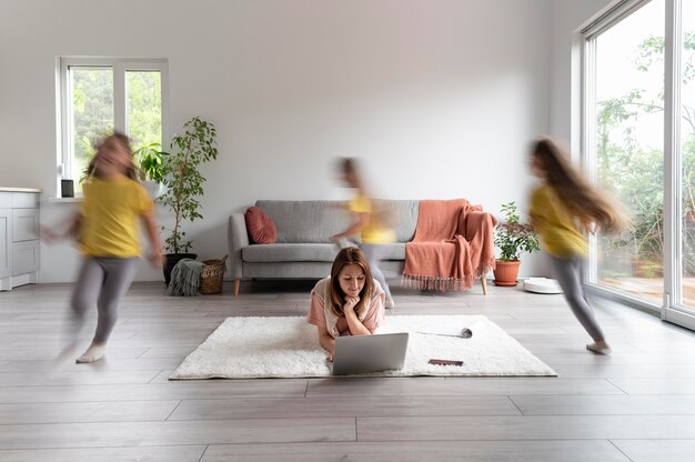 Mujer tratando de trabajar en la computadora portátil desde casa mientras sus hijos corren