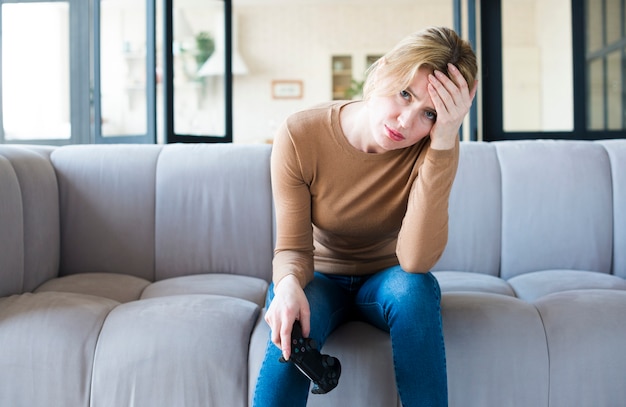 Mujer triste con joystick en el sofá