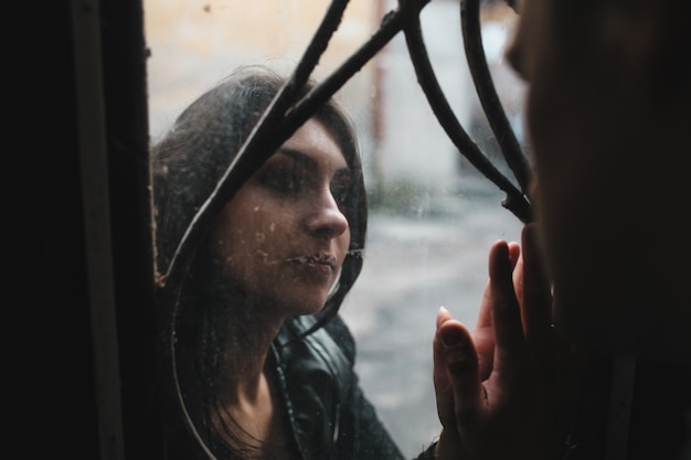 Mujer triste mirando a su novio a través de un cristal