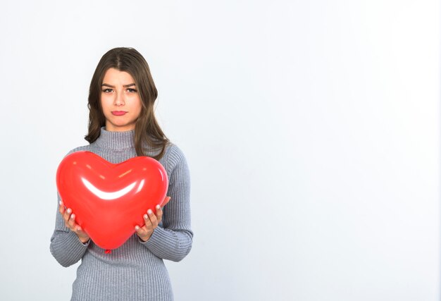 Mujer triste de pie con globo de corazón