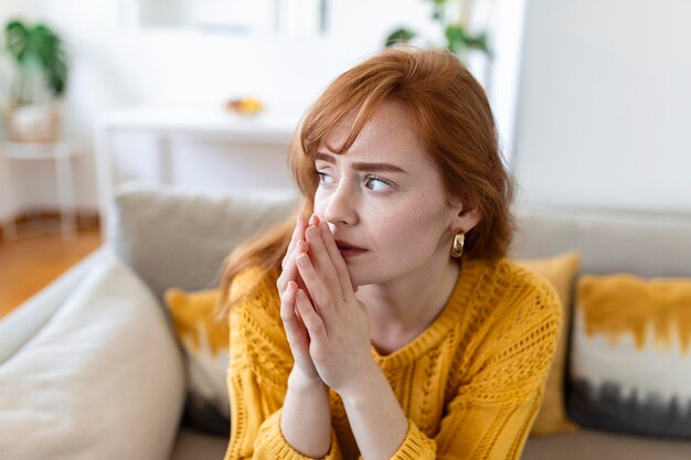 La mujer triste se siente miserable y desesperada sentada en el sofá mirando por la ventana pensando en problemas personales no ve la salida de una situación difícil de la vida Romper el concepto de niña engañada desgarradora