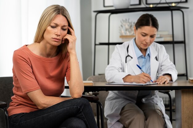 Mujer triste de tiro medio en la cita con el médico.