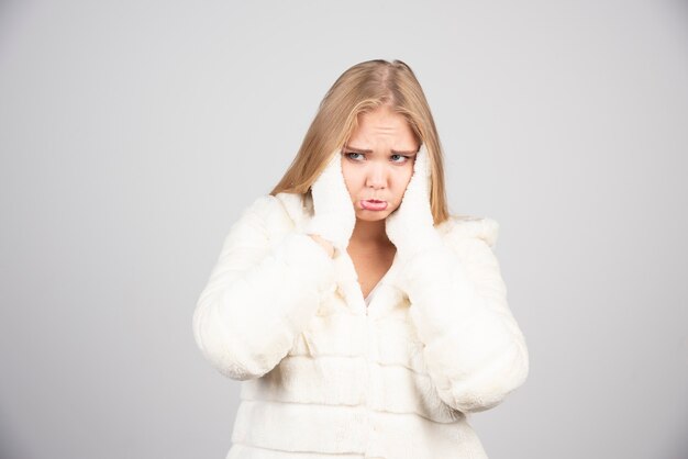 Mujer triste en traje de invierno tapándose los oídos.