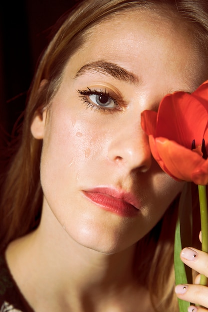 Foto gratuita mujer triste con tulipán rojo