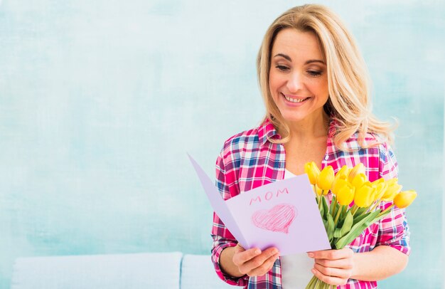 Mujer con tulipanes leyendo tarjeta de felicitación