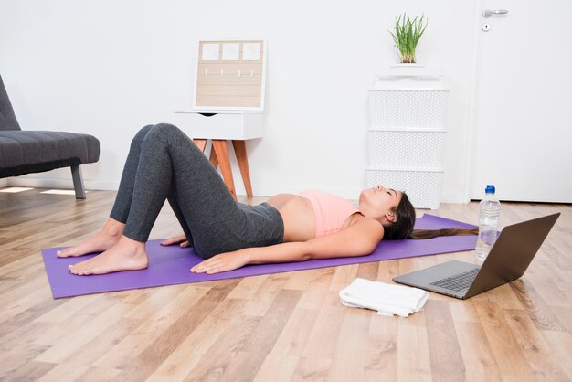 Mujer tumbada en alfombra de yoga