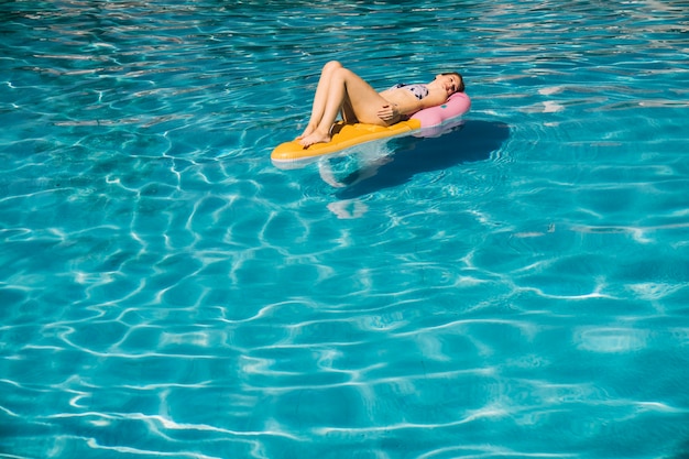 Foto gratuita mujer tumbada en flotador en piscina