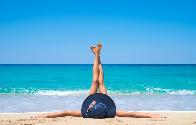 Foto gratuita mujer tumbada en la playa con las piernas en el aire