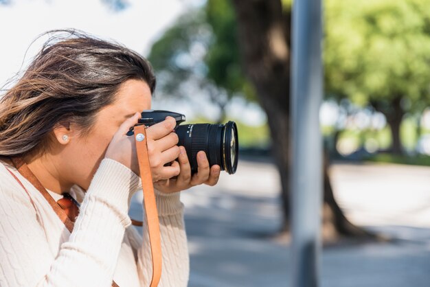 Mujer turista fotografiando desde cámara profesional al aire libre