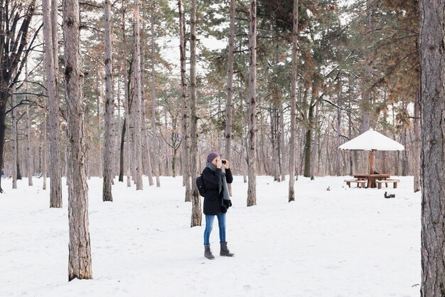 Mujer turista con pie binocular en el bosque de invierno