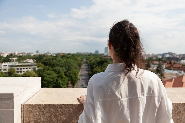 Mujer turista de pie en la terraza de la torre disfrutando de las vacaciones de verano
