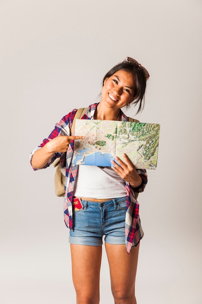 Mujer turista sonriente apuntando a mapa