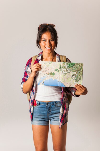 Mujer turista sonriente sujetando mapa