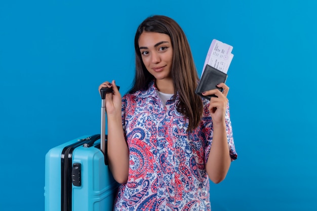 Foto gratuita mujer turista sosteniendo maleta de viaje y pasaporte con boletos con una sonrisa en la cara feliz y positiva