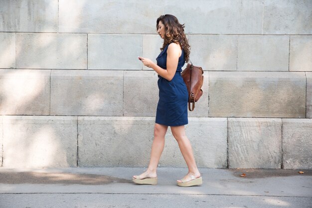 Mujer turística serio caminar y usar el teléfono