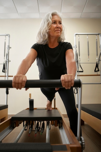 Mujer de último año en clase de pilates reformadora