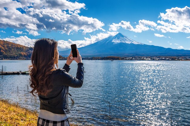 Mujer usa teléfono móvil para tomar una foto en las montañas Fuji, lago Kawaguchiko en Japón.