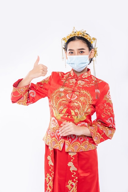 La mujer usa traje Cheongsam y máscara muestra la mejor manera de comprar para proteger la enfermedad
