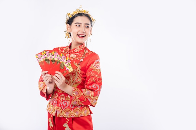 Mujer usa traje Cheongsam sonríe para recibir dinero de regalo de la familia en año nuevo chino