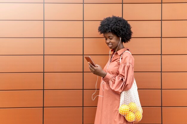 Mujer usando unos auriculares mientras sostiene su teléfono inteligente