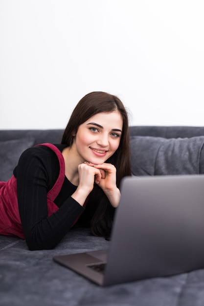 Mujer usando una computadora portátil mientras se relaja en el sofá