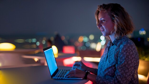 Mujer usando una computadora portátil en la oscuridad