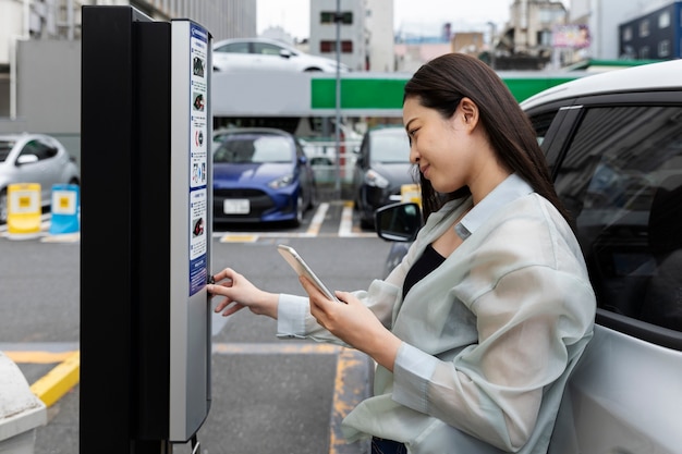 Foto gratuita mujer usando la estación de carga de coches eléctricos