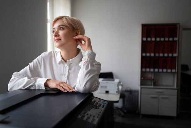 Mujer usando impresora mientras trabaja en la oficina