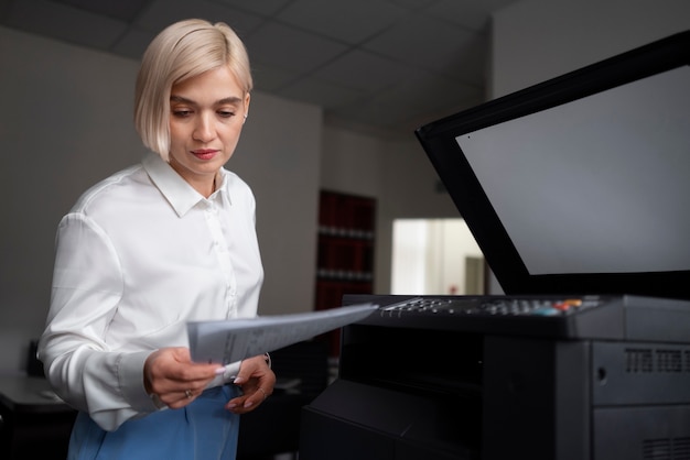 Mujer usando impresora mientras trabaja en la oficina