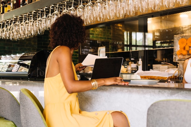 Foto gratuita mujer usando laptop en barra de bar en el restaurante