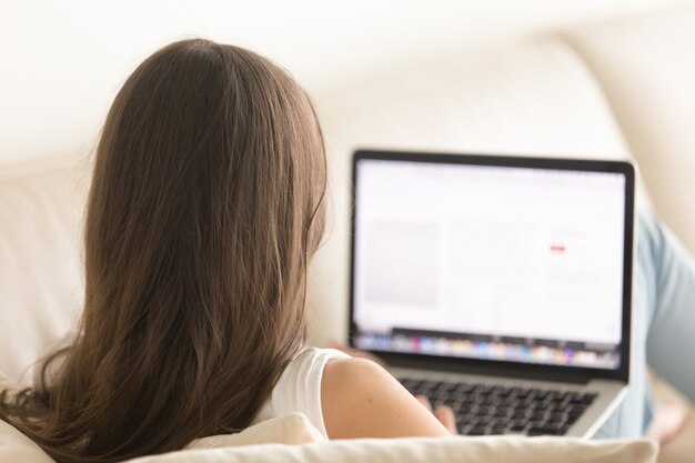 Mujer usando laptop en un cómodo sofá en casa